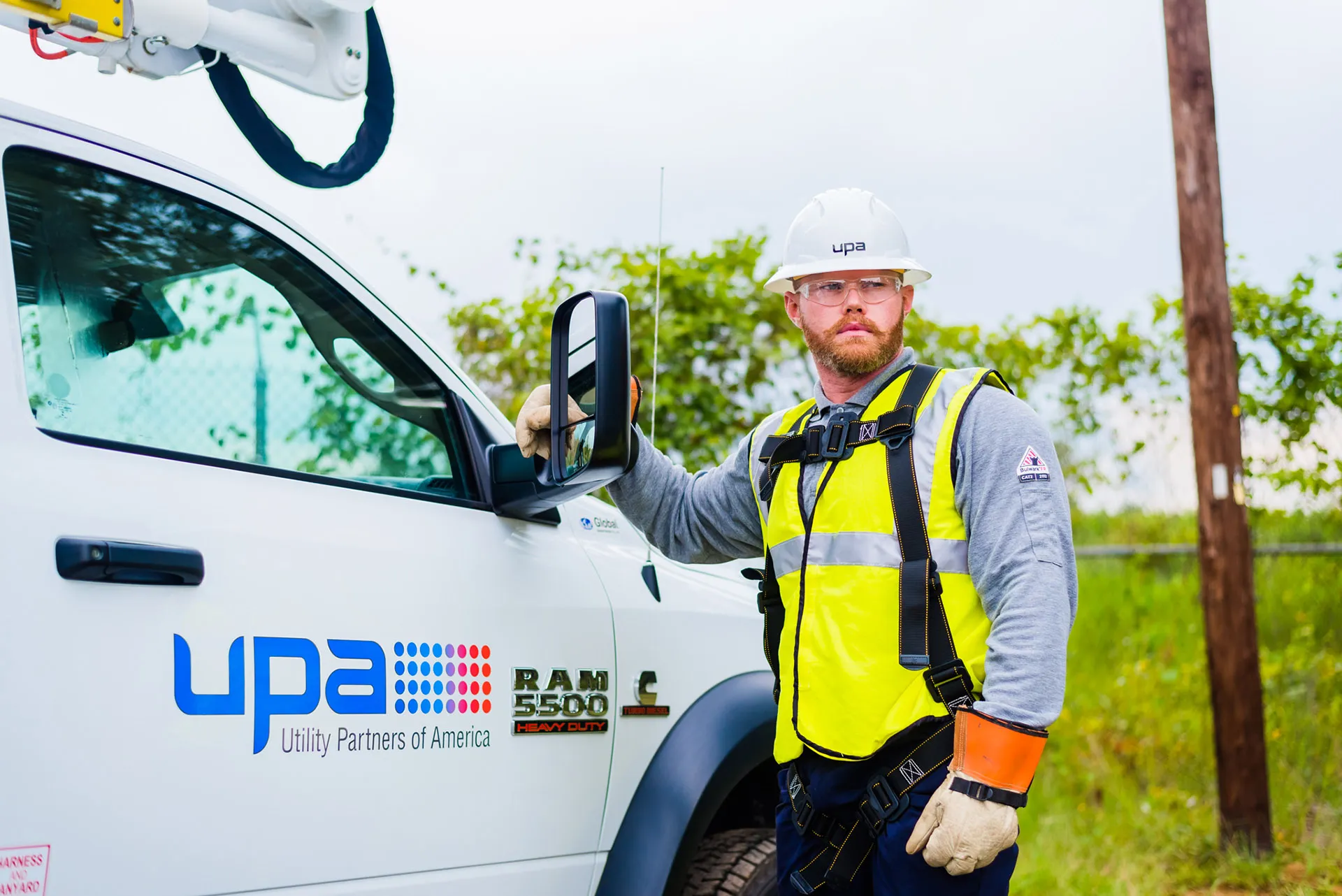 UPA field technician in a hard hat and high-visibility vest beside a bucket truck
