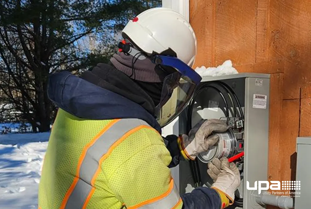 A technician wearing a face shield installs an electric meter