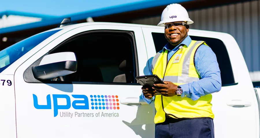 UPA field professional holding a tablet beside a company truck